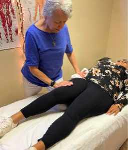 Physical therapist treating patient laying down.